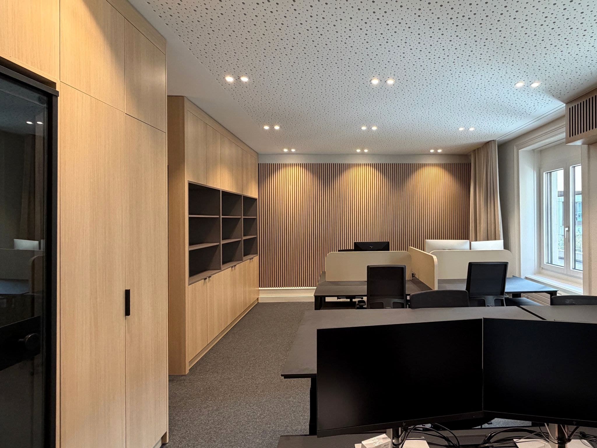 Büro: Arbeitsbereich mit Schrankwand, Regal und Akustiklamellen aus Eiche